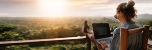 Person watching sunset while using laptop